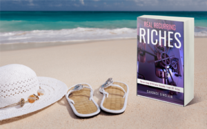 Real Recurring Riches book on the beach with sandals and white hat